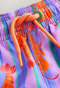 Vasaras peldbikses no viegla auduma ar violets pamatni un apdrukas elementiem — oranži omāri, zaļas svītras un oranža aukla jostasvietā.