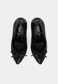 Par crnih baletanki sa špicastim vrhom i vezicama, s vidljivom etiketom "Ryłko Premium Comfort" unutra.