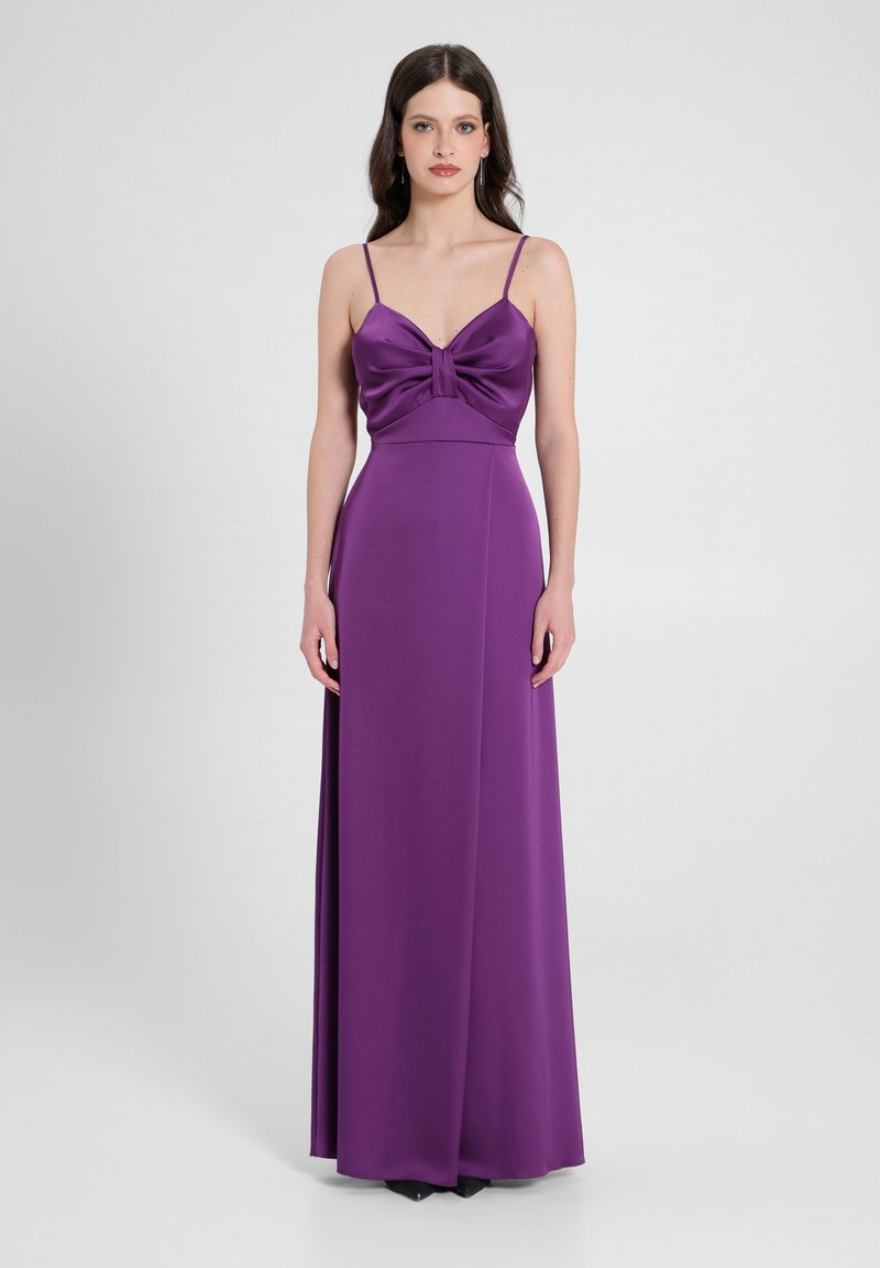 Abito da sera in satin viola con corpetto aderente, dettaglio annodato sul petto e spalline sottili, che si estende in una gonna lunga fino al pavimento.