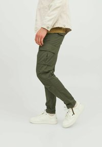 Pantaloni cargo verzi cu multiple buzunare, design cu picioare înguste și țesătură ușoară. Asortați cu adidași albi pentru un look casual.