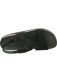 Schwarze Sandale mit einem Obermaterial aus Wildleder, verstellbaren Riemen und einer flachen Sohle. Das Design verfügt über einen atmungsaktiven Zehenbereich und eine glatte Textur.