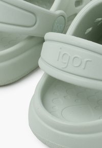 Lysgrønne gummisandaler med en struktureret fodseng og forhøjede prikker. Har en bred rem med mærket "igor" præget på.