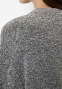 Maglione grigio a maglia con scollatura rotonda, dettagli a coste e una texture morbida. Il tessuto presenta un sottile motivo melangiato.