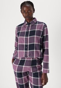 Langermige, knoopsluiting geruite blouse in paars en marineblauw met witte accenten. Bijpassende broek met elastieke tailleband, featuring een vergelijkbaar patroon.