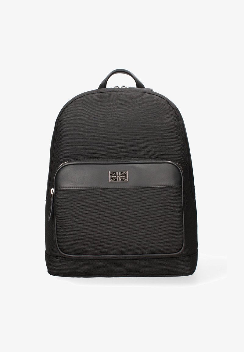 Zwarte rugzak met een textuurstof buitenkant, een voorzak met rits en een metalen logo-plaquette met een Union Jack ontwerp. Rond gevormd.