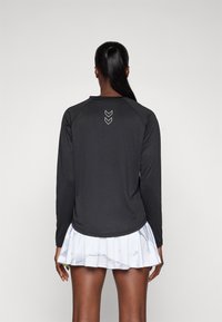 Zwarte sporttop met lange mouwen, een gladde textuur, een ronde halslijn en een subtiel wit v-vormig patroon op de achterkant.