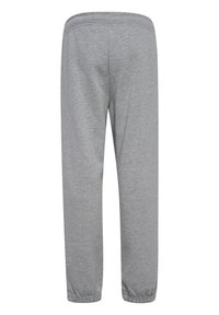 Jasnoszare spodnie dresowe z elastycznym pasem i ściągaczami, widoczne z tyłu, wykonane z miękkiego bawełnianego materiału, luźny krój.