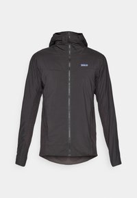 Veste légère noire avec une capuche ajustée, fermeture éclair à l'avant et panneaux latéraux texturés. Présente un petit logo sur la poitrine et un ourlet arrondi.
