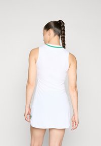 Weißes ärmelloses Kleid mit figurbetontem Schnitt, grünem Kragenakzent und weicher Textur. Verfügt über ein seitliches Detail am Saum.