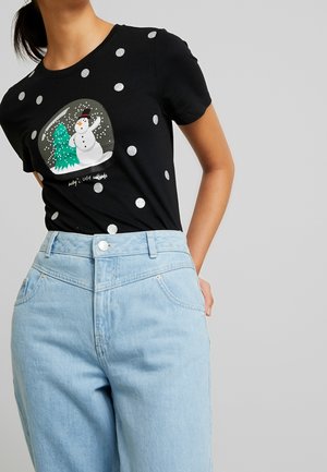 T-shirt nera con pois argentati e grafica frontale che presenta un pupazzo di neve e un albero. Abbinata a jeans a vita alta di colore blu chiaro.