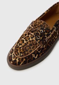 Sko med leopardmønster og myk pelsstruktur, med brune detaljer, to hull for lisser, og en slitesterk gummisåle.