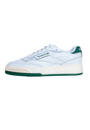 Sneaker bianca Reebok con dettagli verdi, design con lacci e logo del marchio su lato e tallone, mostrata di profilo su sfondo bianco.