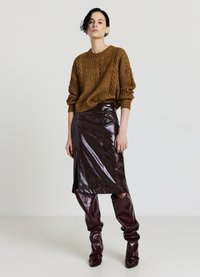 Brauner gestrickter Pullover mit Zopfmuster, kombiniert mit einem glänzenden bordeauxroten Lederrock und kniehohen passenden Stiefeln.