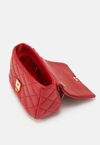 Κόκκινη τσάντα χειρός με καπιτονέ υφή, χρυσό κούμπωμα και αλυσίδα για ιμάντα. Ανοιχτό καπάκι αποκαλύπτει εσωτερικές θήκες και επένδυση.