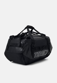 Sac de sport noir avec une finition texturée, doté de plusieurs sangles, d'une grande fermeture éclair et du logo "TERREX" en blanc sur le côté.
