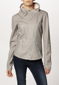 Giacca texturizzata grigio chiaro con collo alto, zip asimmetrica e due tasche laterali. Presenta un rivestimento interno liscio, che aggiunge contrasto.
