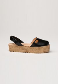 Sandal de plataforma negro con punta abierta, que cuenta con una suela media de yute trenzado y una parte superior elegante con un acento decorativo del logo en el costado.