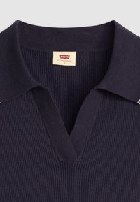 Polo-shirt bleu marine à côtes avec un col en V et un col tricoté. L'étiquette indique "Levi's, San Francisco, Cal." Taille S. Texture lisse et ajustée.