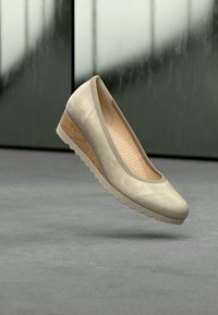 Ballerinas in metallic beige met een gladde textuur, een afgeronde neus en een kurken sleehak. Voorzien van een geperforeerd voetbed voor ademend vermogen.