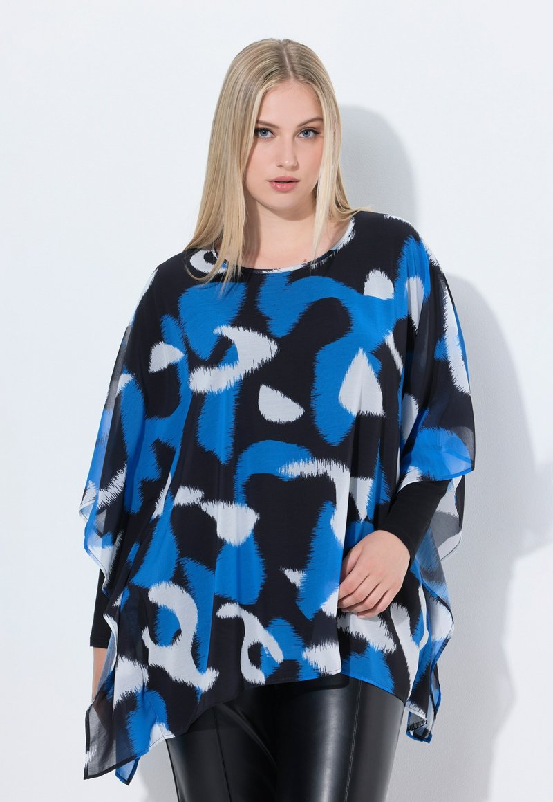 Top nero fluido con motivi astratti blu e bianchi. Presenta un colletto arrotondato e maniche ampie. Abbinato a leggings in pelle nera.