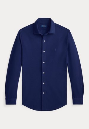 Chemise bleue marine à manches longues, boutonnée, avec col et petit logo brodé sur la poitrine.