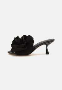 Sorte semskede åpne tå mules med en stor stoffvolang foran, en slank hæl og et jevnt, buet design.