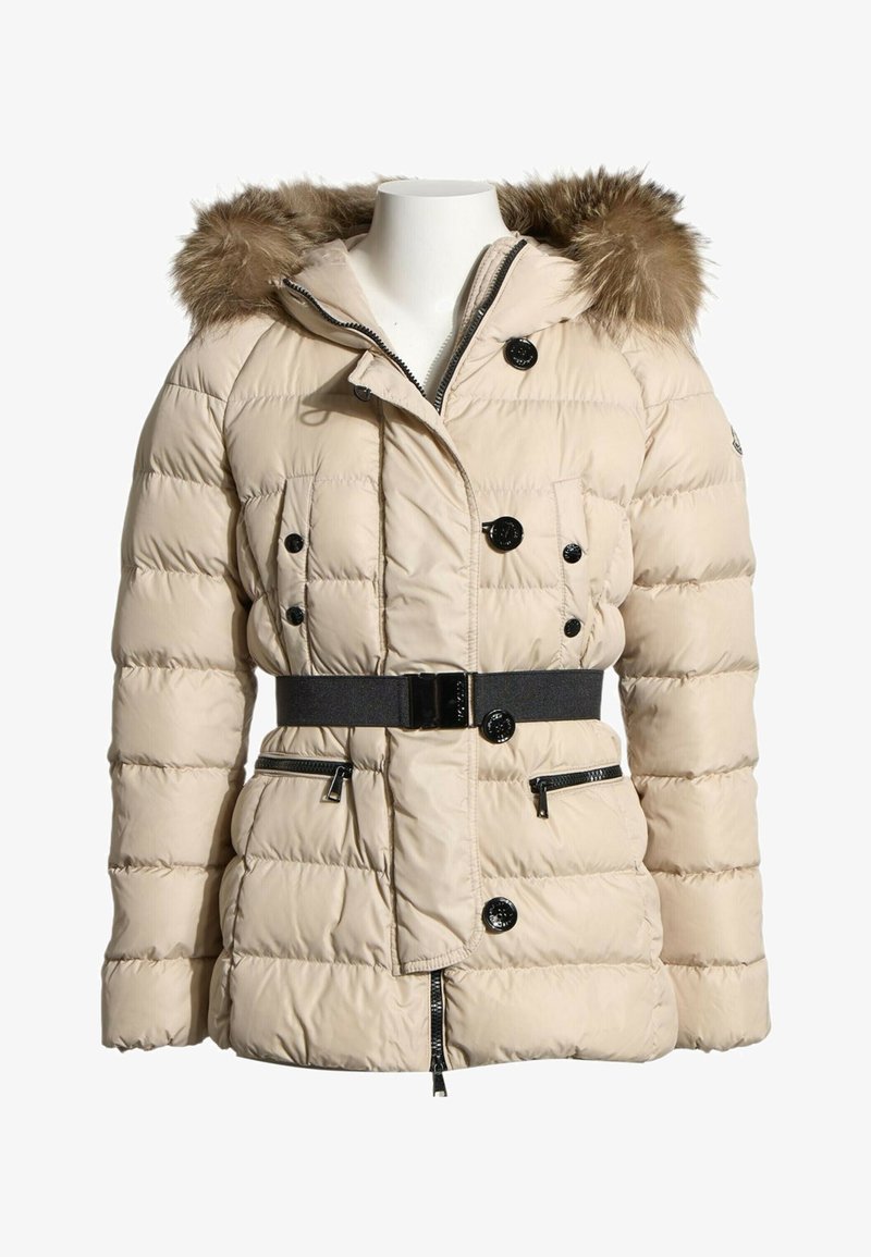 Veste d'hiver matelassée beige avec capuche bordée de fourrure, boutons noirs, poches zippées et ceinture noire à la taille.