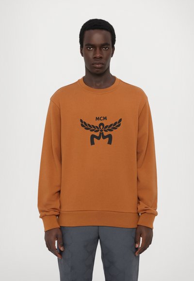 Sweatshirt marron à manches longues, col rond, avec un logo graphique noir centré sur la poitrine. Tissu doux en mélange de coton.