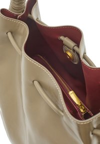 Beżowa skórzana torebka o miękkiej fakturze, z głębokoczerwonym wnętrzem, kieszenią na zamek i złotymi elementami wykończenia.