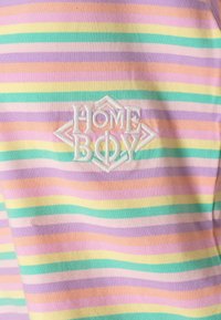 Koszulka w paski w pastelowych kolorach: różowym, lawendowym, miętowym i brzoskwiniowym. Posiada haftowane logo "HOME BOY" w białym kolorze na tle w kształcie diamentu.