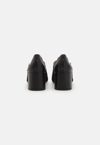 Black high-heeled shoes with a textured upper and smooth leather accents. Block heel provides stability. Classic design with sleek lines.