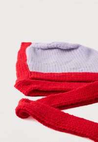 Balaclava tricotată în roșu și mov deschis. Prezintă șnururi lungi roșii și un model tricotat texturat. Secțiuni de culori variate cu tranziții line.