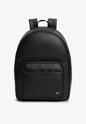 Mochila negra con textura, con bolsillo frontal con cremallera, correas acolchadas para los hombros y pequeño logotipo rectangular en la esquina inferior derecha.