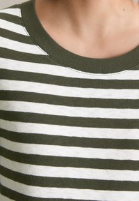 Green and white striped top, made of soft fabric. Features a ribbed neckline and horizontal stripes with moderate texture.