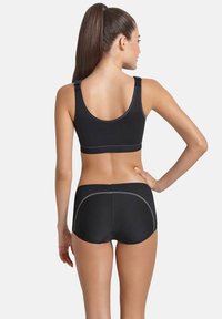 Schwarzer Sport-BH mit verstellbaren Trägern und glatter Textur, kombiniert mit schwarzen Shorts, die Netzakzente und graue Stickdetails aufweisen.