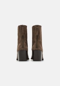 Brune suède ankelstøvler med en tapered design, med en bakre glidelås og en solid hæl, glatt tekstur og subtile sømdetaljer.