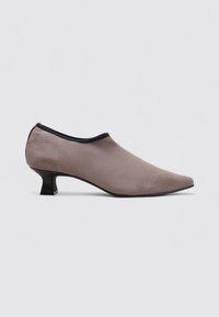 Zapato de ante gris con punta afilada, ribete negro y tacón bajo y brillante. Diseño elegante con textura suave y detalles mínimos.