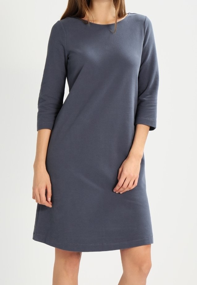 Robe en jersey grise avec un col rond, des manches trois-quarts et une coupe ample, présentant un ourlet qui tombe juste au-dessus du genou.