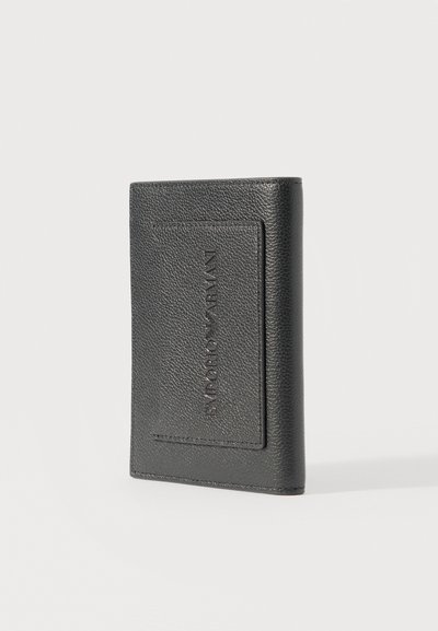 Μαύρο πορτοφόλι από δερματίνη με υφή, όρθιο, με ανάγλυφο λογότυπο Emporio Armani στην μπροστινή τσέπη, σε απλό φόντο.