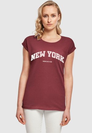 Mørkerød t-shirt med opbrettede ærmer, der har hvid tekst "NEW YORK" og "MERCHCODE" på et blødt stof. Enkel, afslappet design.