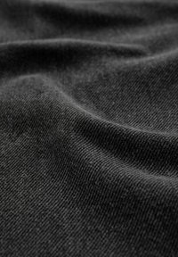 Tissu noir texturé avec une surface douce et un motif de tissage visible, présentant des plis délicats et une apparence lisse.