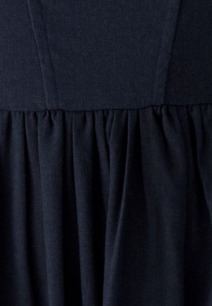 Tumesinine kleit tekstureeritud kootud kangaga. Vöörihmaga istuv ülaosa ja volditud seelik, mis loob allosas vooluva silueti.