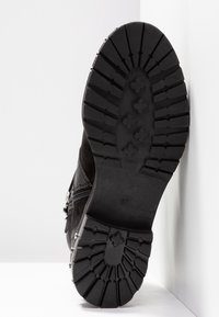 Stivale in suede nero, con suola in gomma robusta caratterizzata da tacchetti profondi e borchie decorative argentate lungo il lato. Taglia 37 indicata sulla suola.