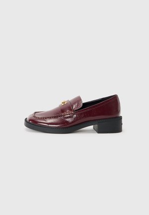 Burgundy leather loafer with a glossy finish, featuring a stitched seam, rounded toe, and a low block heel. Gold hardware accent detail.