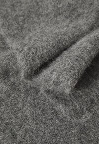 Gray felt fabric with a loose, fuzzy texture, showcasing soft fibers and layered folds. The surface appears durable and slightly mottled.