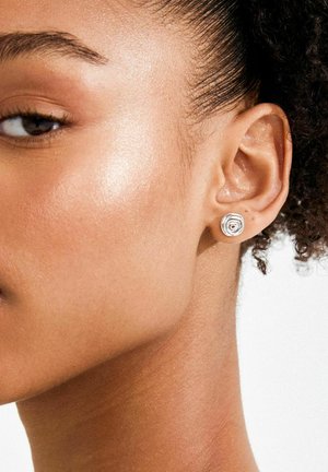 Sudraba spirāles formas auskari ar teksturētu virsmu un apļveida dizainu papildina ausi ar minimālisma estētiku.