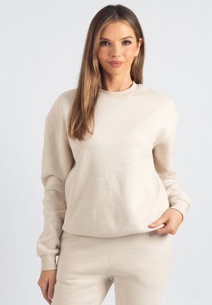 Beiges Baumwoll-Sweatshirt mit Rundhalsausschnitt, gerippten Bündchen und lockerem Sitz. Glatte Textur, leichtes Material, kombiniert mit passenden Unterteilen.