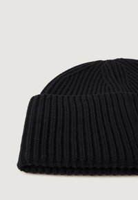 Beanie nero a coste con risvolto, caratterizzata da una texture morbida e un design senza cuciture sulla sommità. Leggera e aderente.