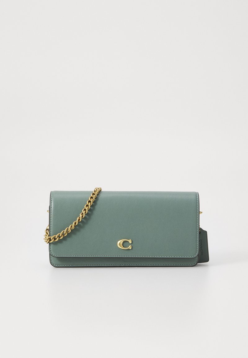 Green leather handbag with a chain strap, featuring a gold-tone logo accent and a sleek, rectangular design. Smooth texture.
