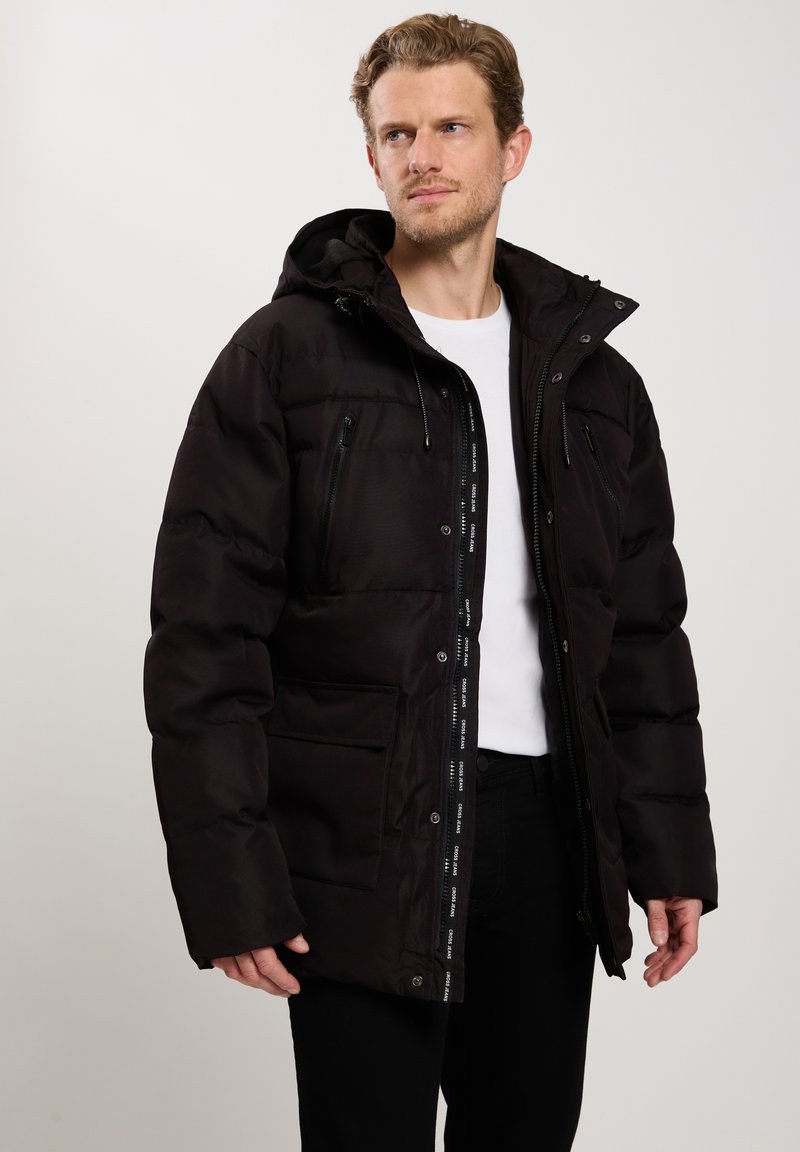 Czarna kurtka puchowa z kapturem, z zapięciem na zamek błyskawiczny, wieloma kieszeniami na zamek oraz kontrastowymi metkami wewnętrznymi. Teksturowana tkanina o gładkim wykończeniu.